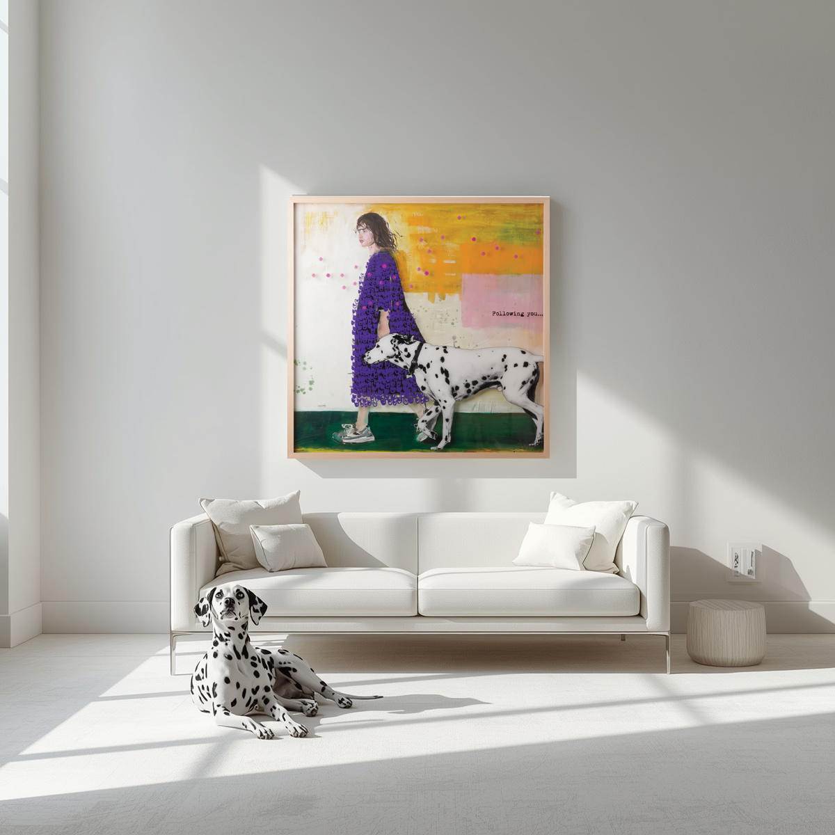 Peinture originale contemporaine 1m x 1m "Following you" de Béatrice Graas, exposée dans un salon moderne lumineux. L'œuvre représente une femme et un dalmatien, accrochée au-dessus d'un canapé blanc avec un vrai dalmatien au premier plan.